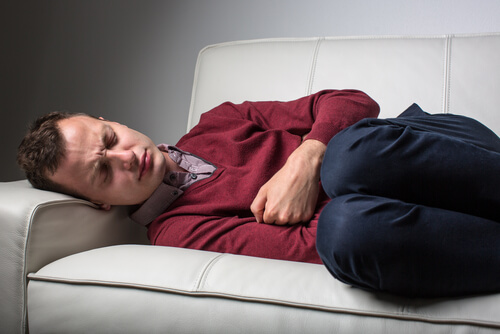 man lying on sofa in pain