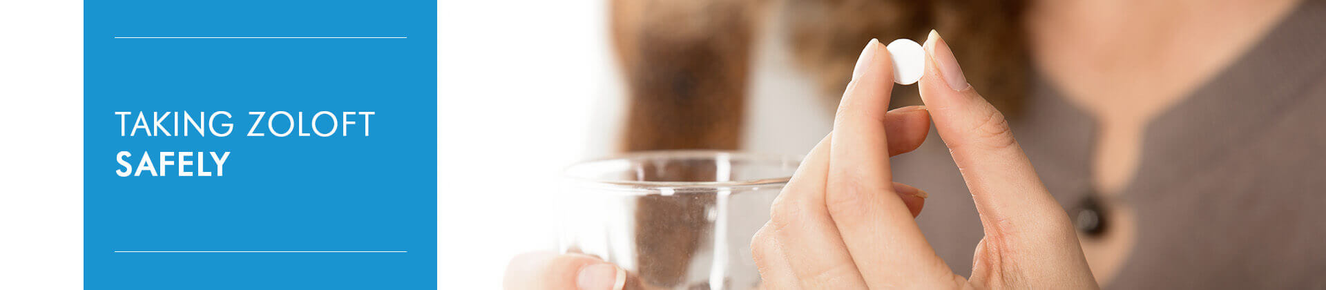 female hands holding one white round pill and glass of water