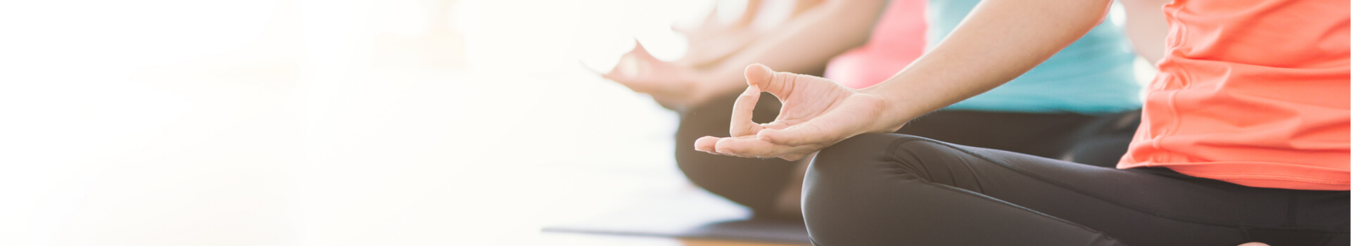 group of women sitting in lotus pose in yoga class