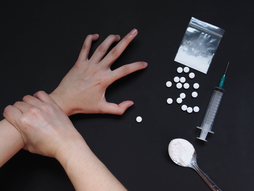 Drug addict's hand is touching pills