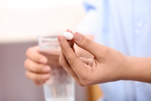 Woman holding wellbutrin pill and glass of water