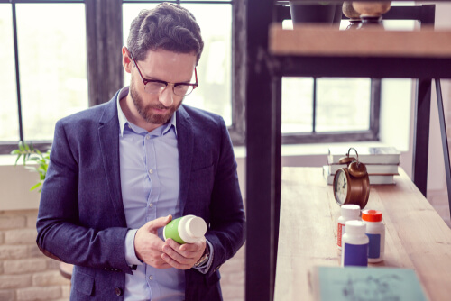 man looking at the bottle with pills