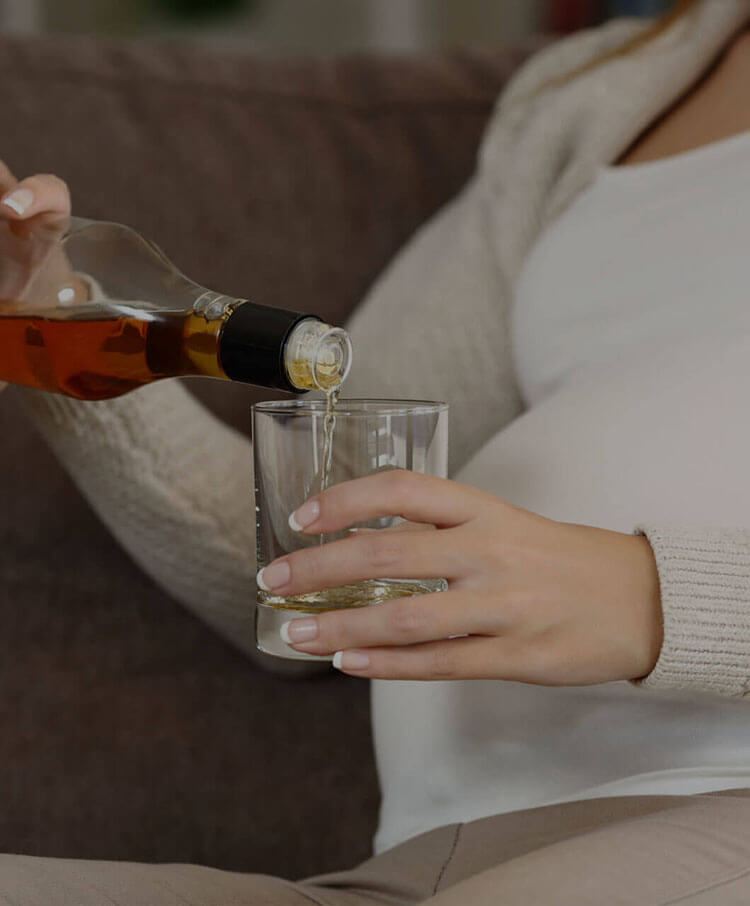 pregnant woman pouring alcohol in glass
