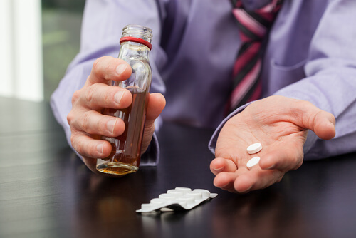 Mann, der Tabletten mit Alkohol einnimmt