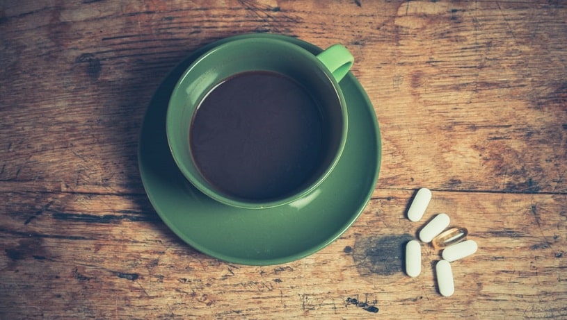 A cup of black coffee with six pills of adderall.