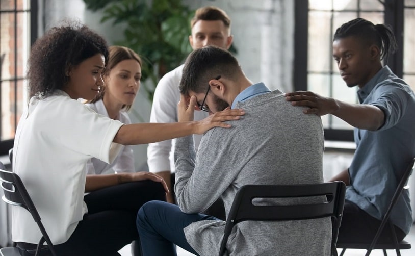 Group of people support a sad man.