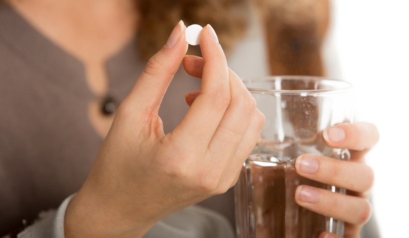 Woman taking Naproxen pill.