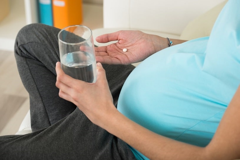 Pregnant woman taking Aleve pills.