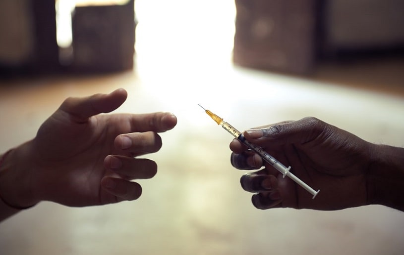 two men sharing needle for heroin injection.