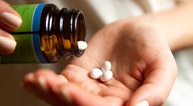 A young woman pours Percocet pills out of the bottle.