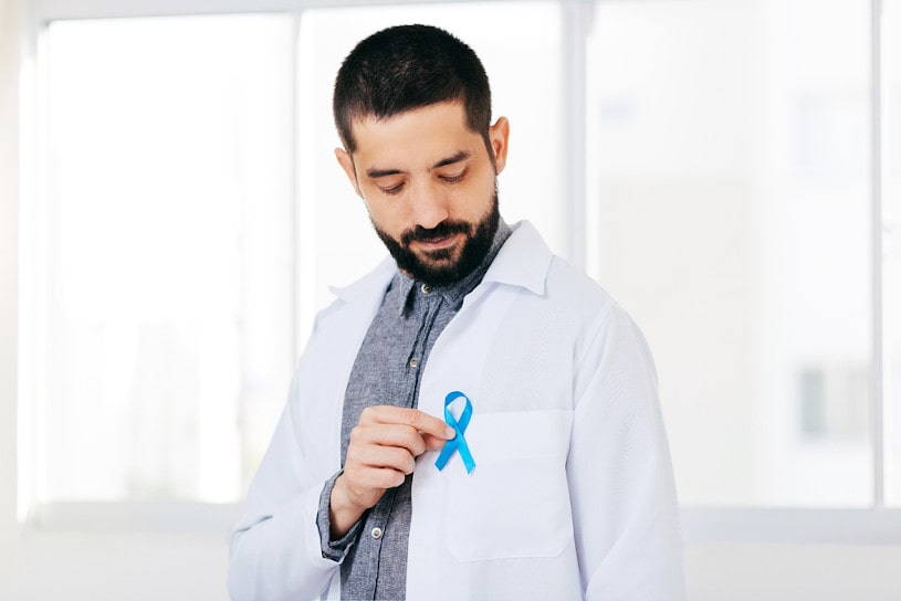 Doctor man holding light Blue Ribbon for supporting prostate cancer awareness.