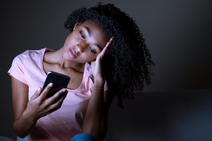 black girl holding phone at night.