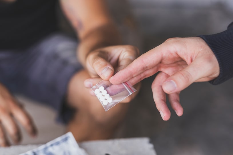 A guy gives another guy a sachet of MDMA pills.