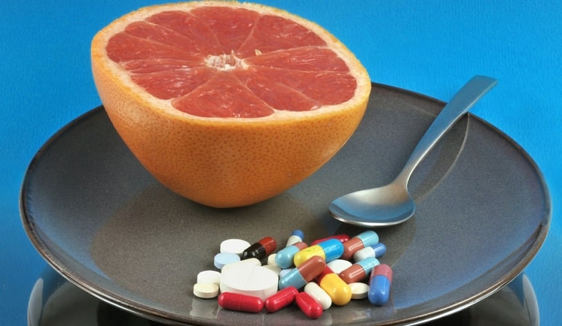 Half grapefruit in a plate with assorted medicines.