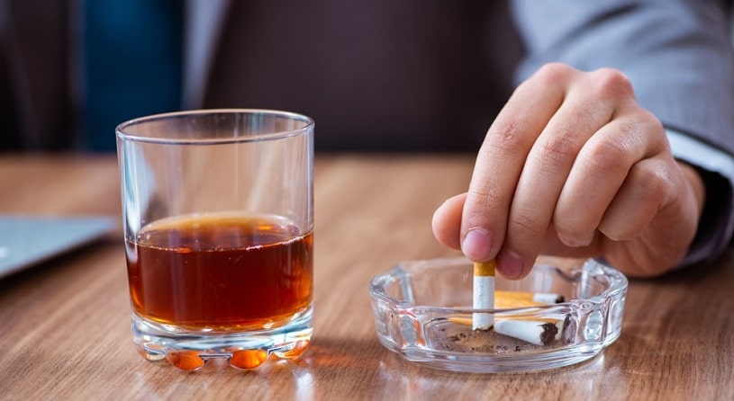 Man drinking alcohol and smoking.