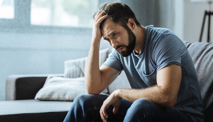 Sad gloomy man holding his forehead.