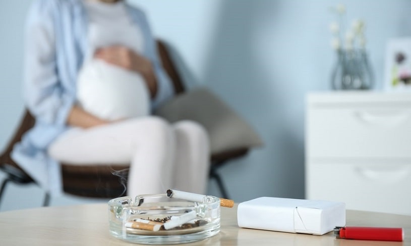 Pregnant woman and cigarettes on the table.