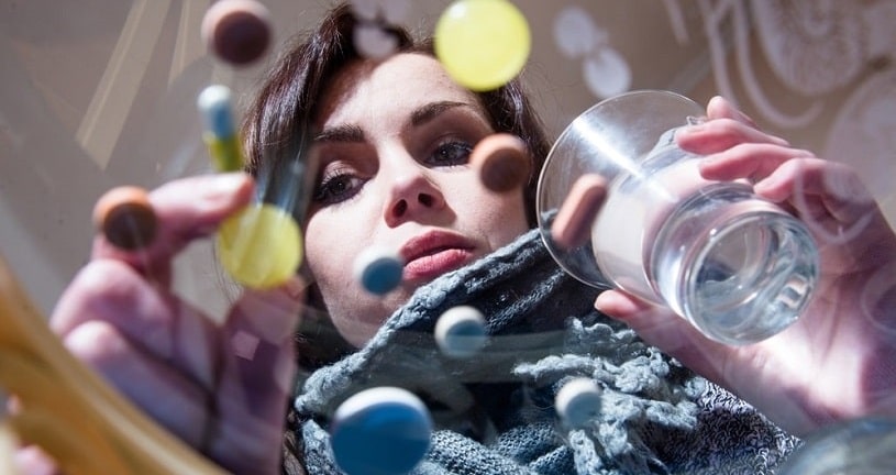 Addicted girl looking at phenibut capsules.