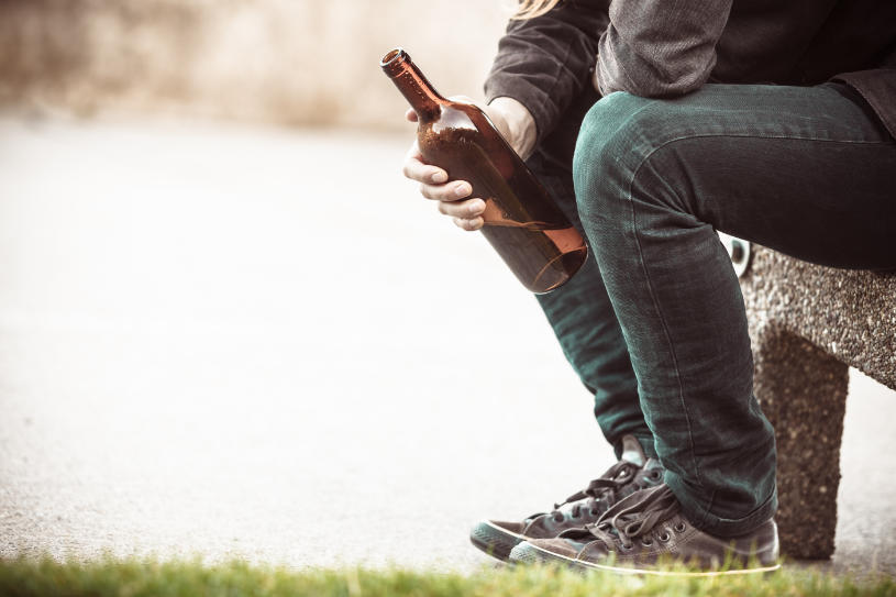 A drunk man sitting with a bottle of beer.