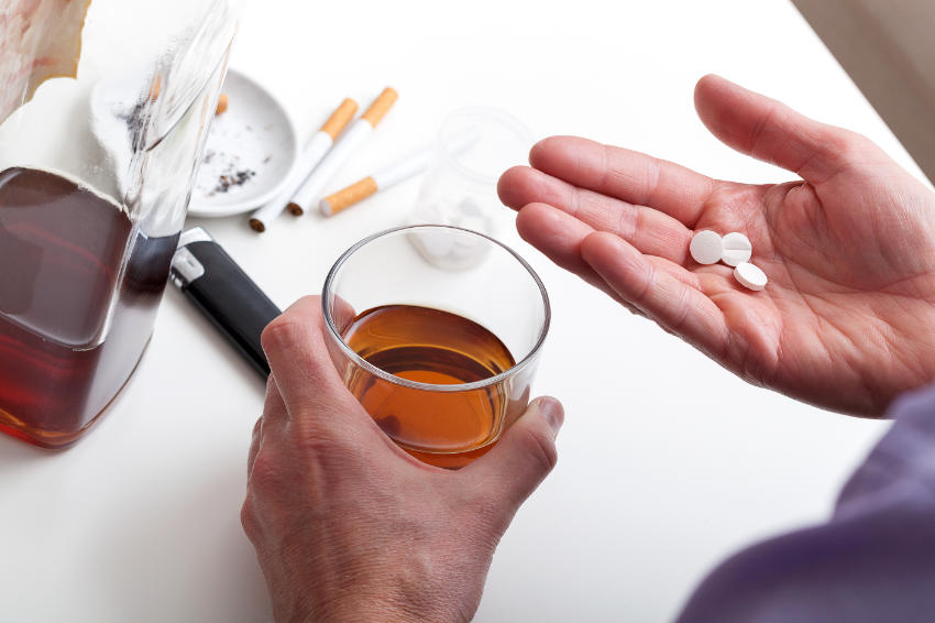 A man holds a Lexapro pill and Alcohol, Interaction of medications and alcohol is always dangerous.
