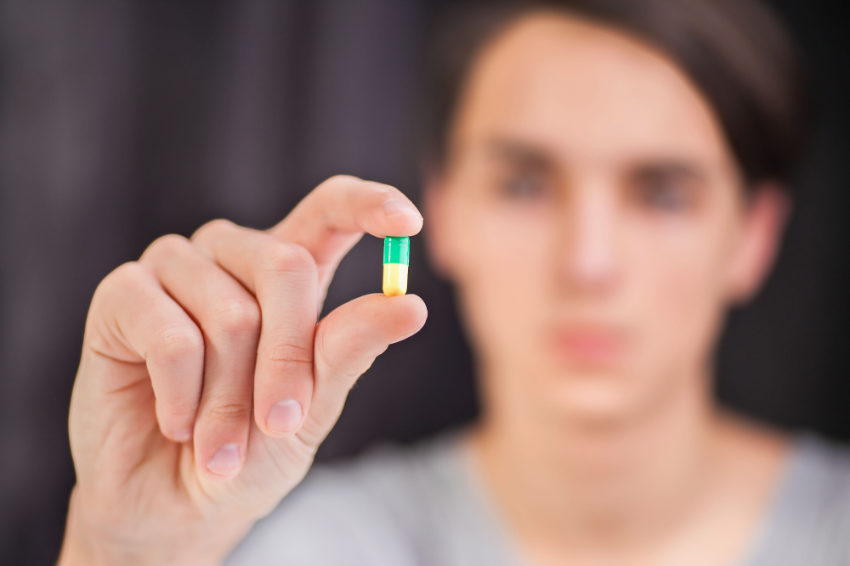 A man holds a Lexapro pill in his hand.