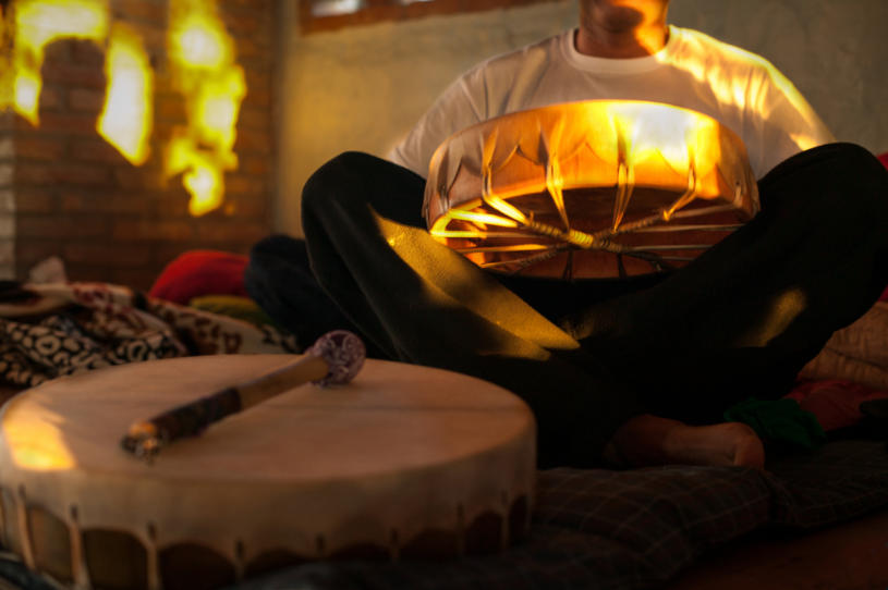 A man siting on the ground with a drum.