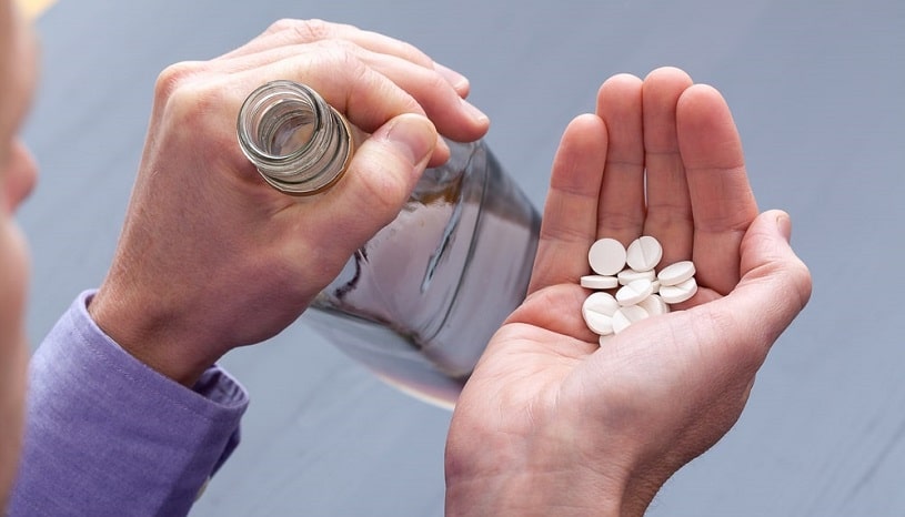 Man holding Seroquel and vodka bottle in hands.