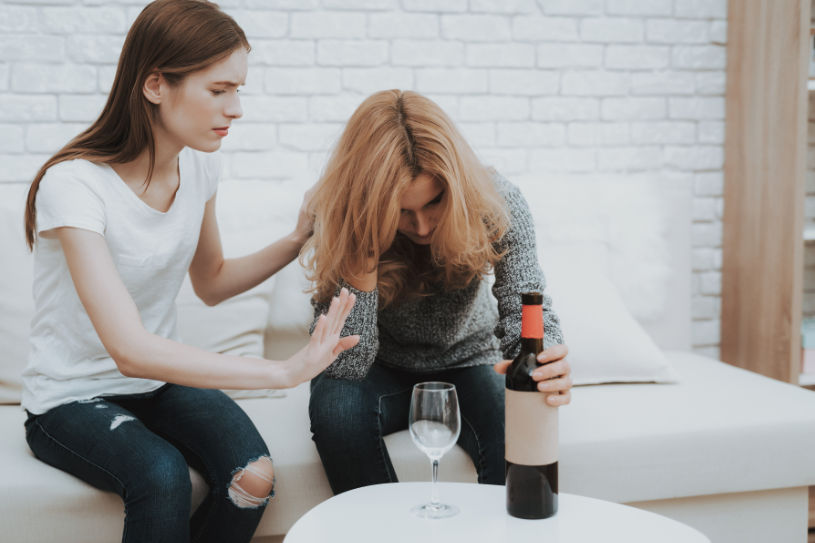 een vrouw steunt een andere vrouw die stopt met het drinken van alcohol.