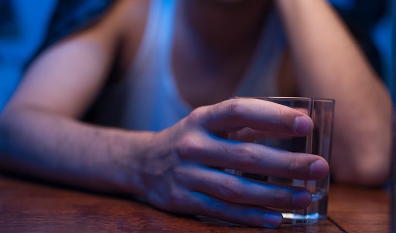 An alcoholic at the table with a glass of alcohol.