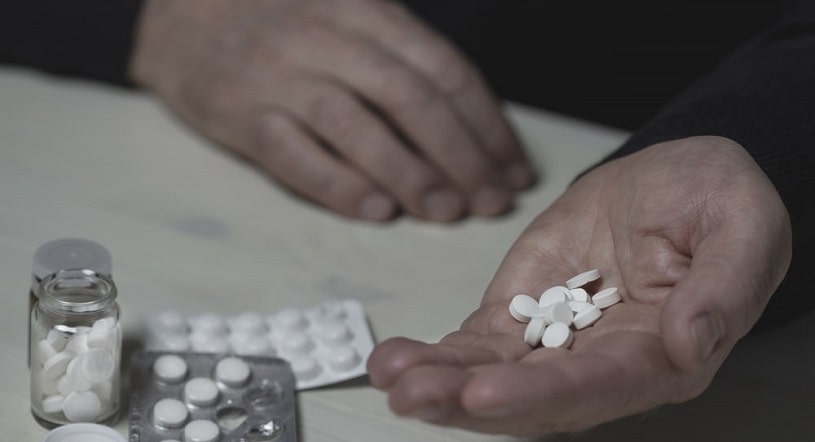 Man holds a lot of pills in the hand.
