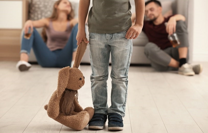 Little boy is ignored by parents who drink alcohol on the background.