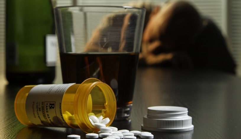 A man overdosed on Valium and alcohol, pills and alcohol on table.
