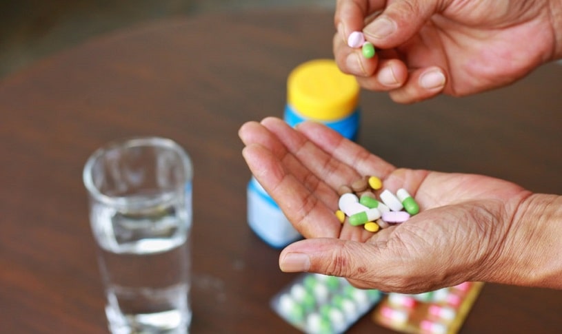 Man holding many pills and capsules in hands.