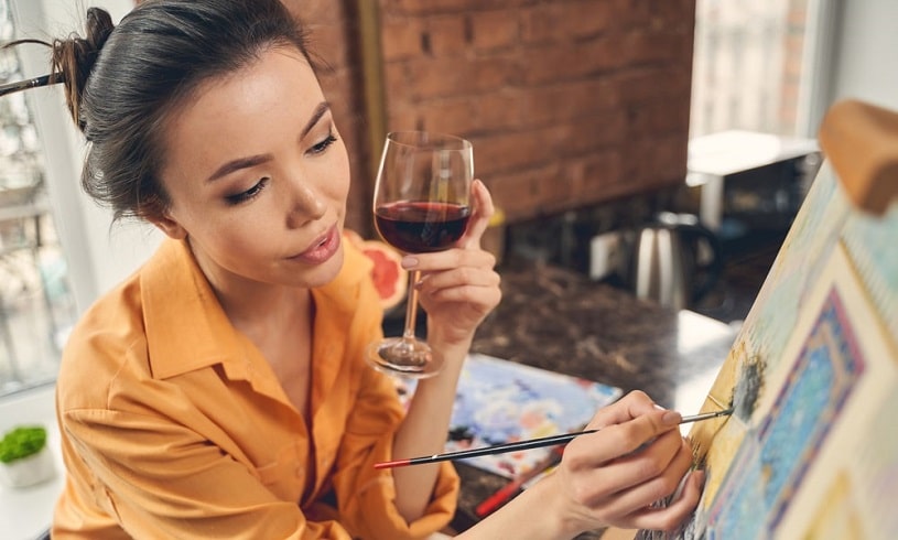 Girl painting and drinking wine.