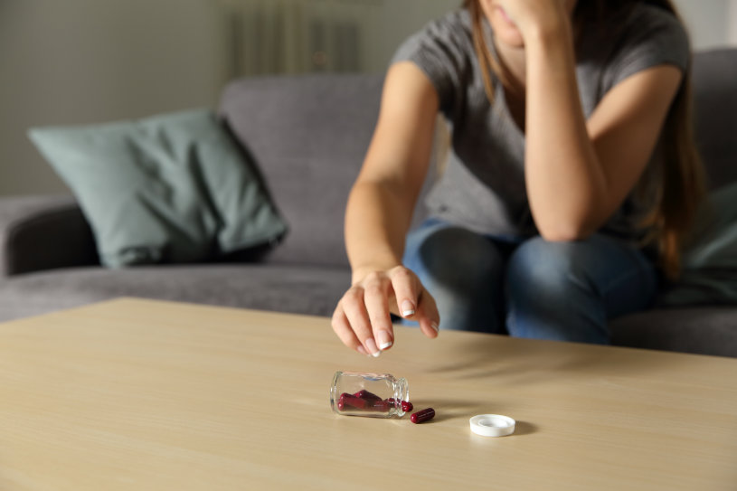 A woman is suffering from Viibryd side effects and has dropped pills on the table.