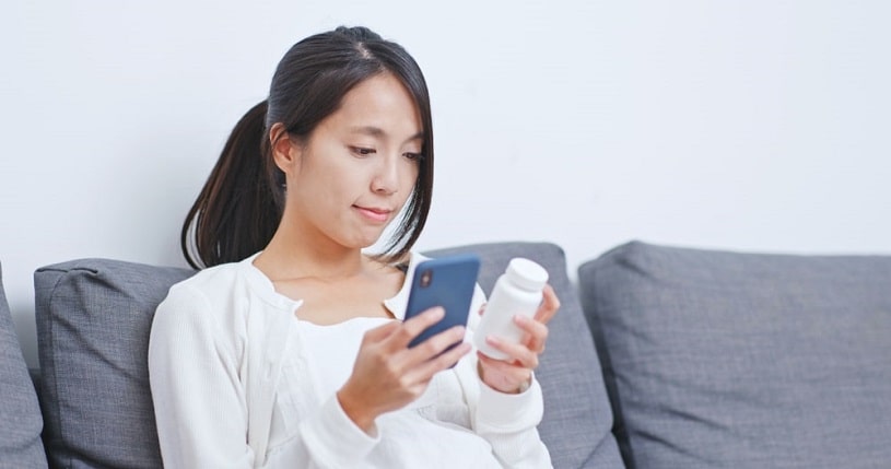 Woman reading about Adderall and Strattera differences on the phone.