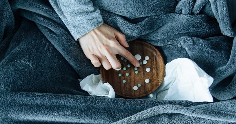 Woman sitting on sofa choosing pills.