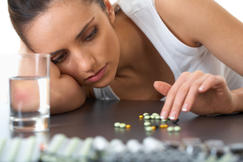 A woman addicted to Amitriptyline pills watches at them lying on the table.