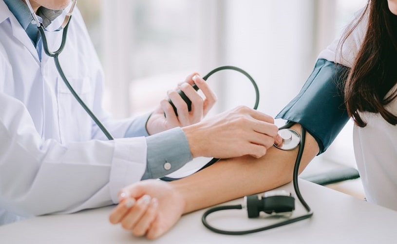 Doctor using stethoscope to measure blood pressure.