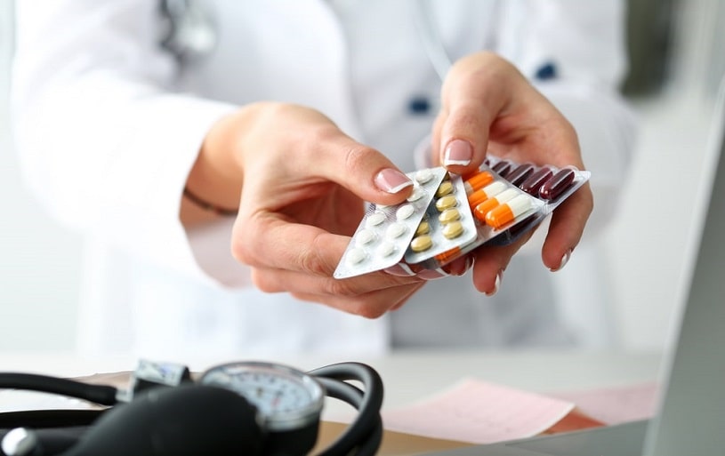 Female doctor hand holding a pack of different pills.