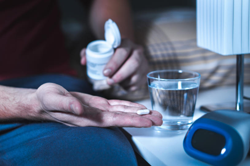 A man holds a pill in his hand and experiences Kava side effects.