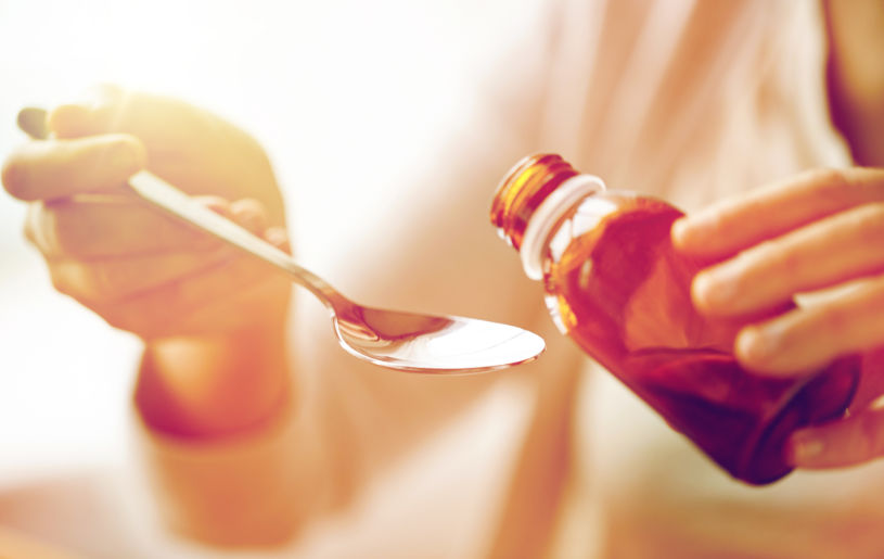 A woman pours DXM cough syrup in the spoon.