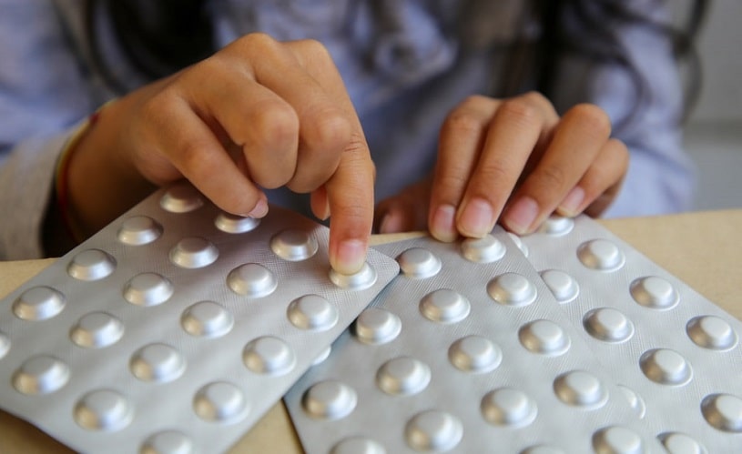 Girl holding blisters of stimulant pills, choosing among them.