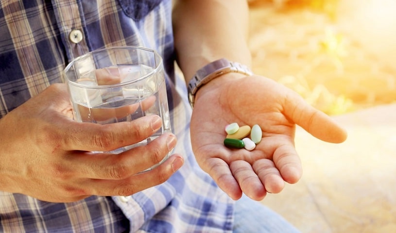 A man taking Meloxicam medication with a glass of water.