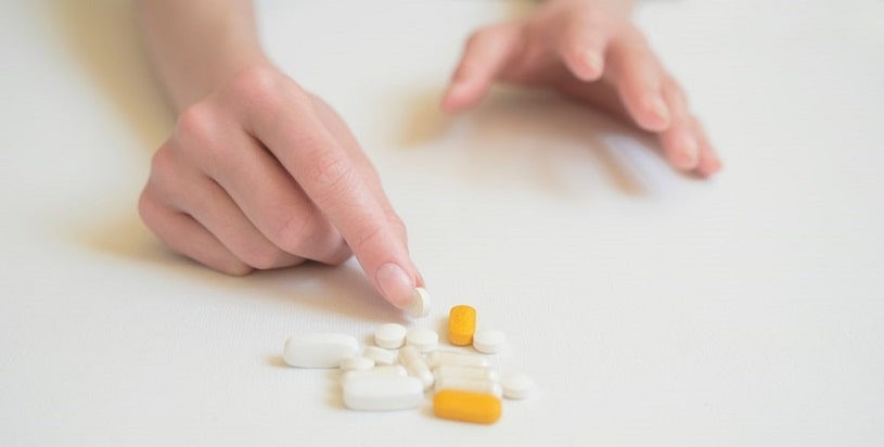 Woman choosing pills on the table.