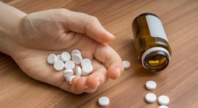 Woman's hand holding many oxycodone pills.