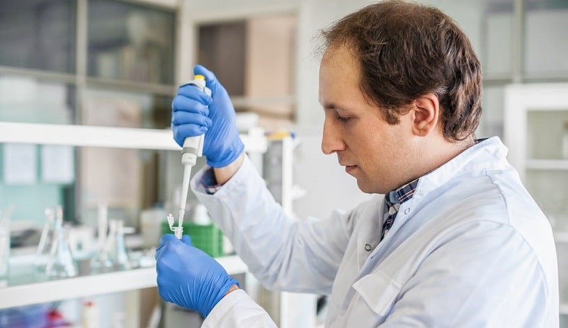 Male scientist filling test tubes.