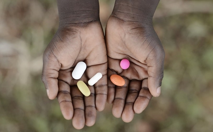 A person holding meloxicam and tylenol pills.