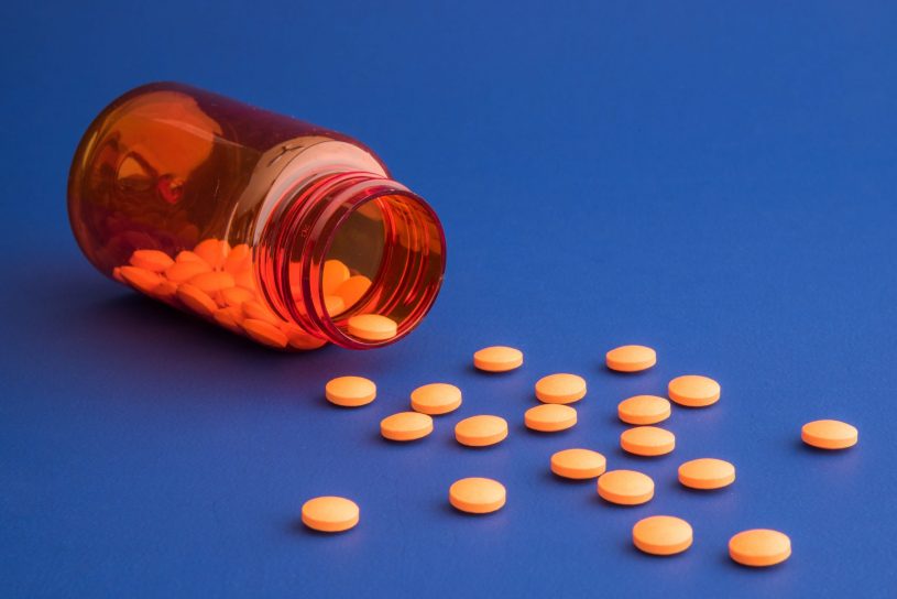 Orange Naloxone pills spilled from the bottle.