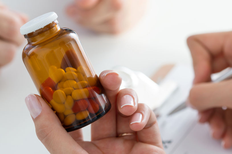 A doctor holds Vyvanse pills and writes a prescription.